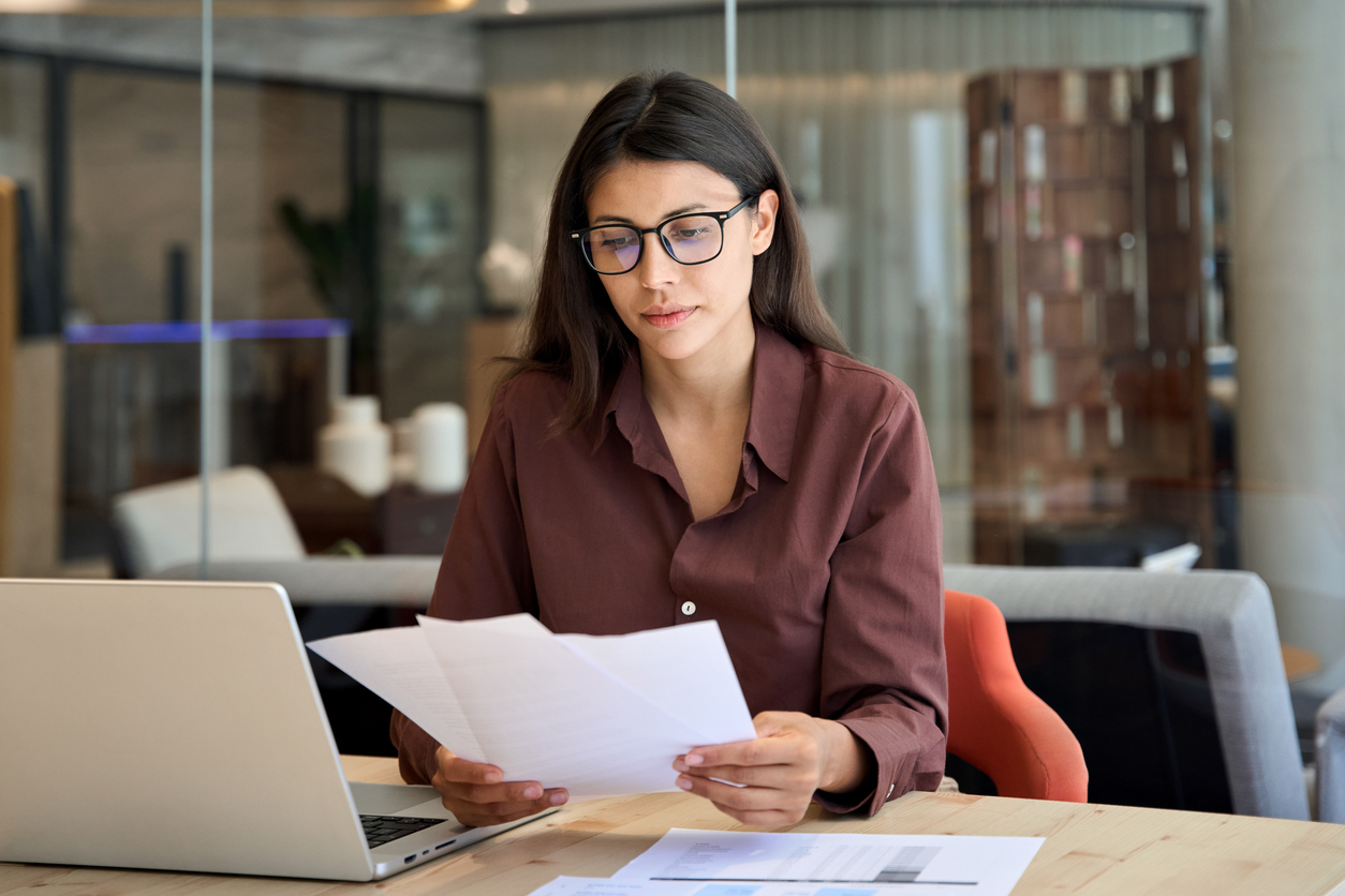 business woman working on laptop computer reading financial documents
