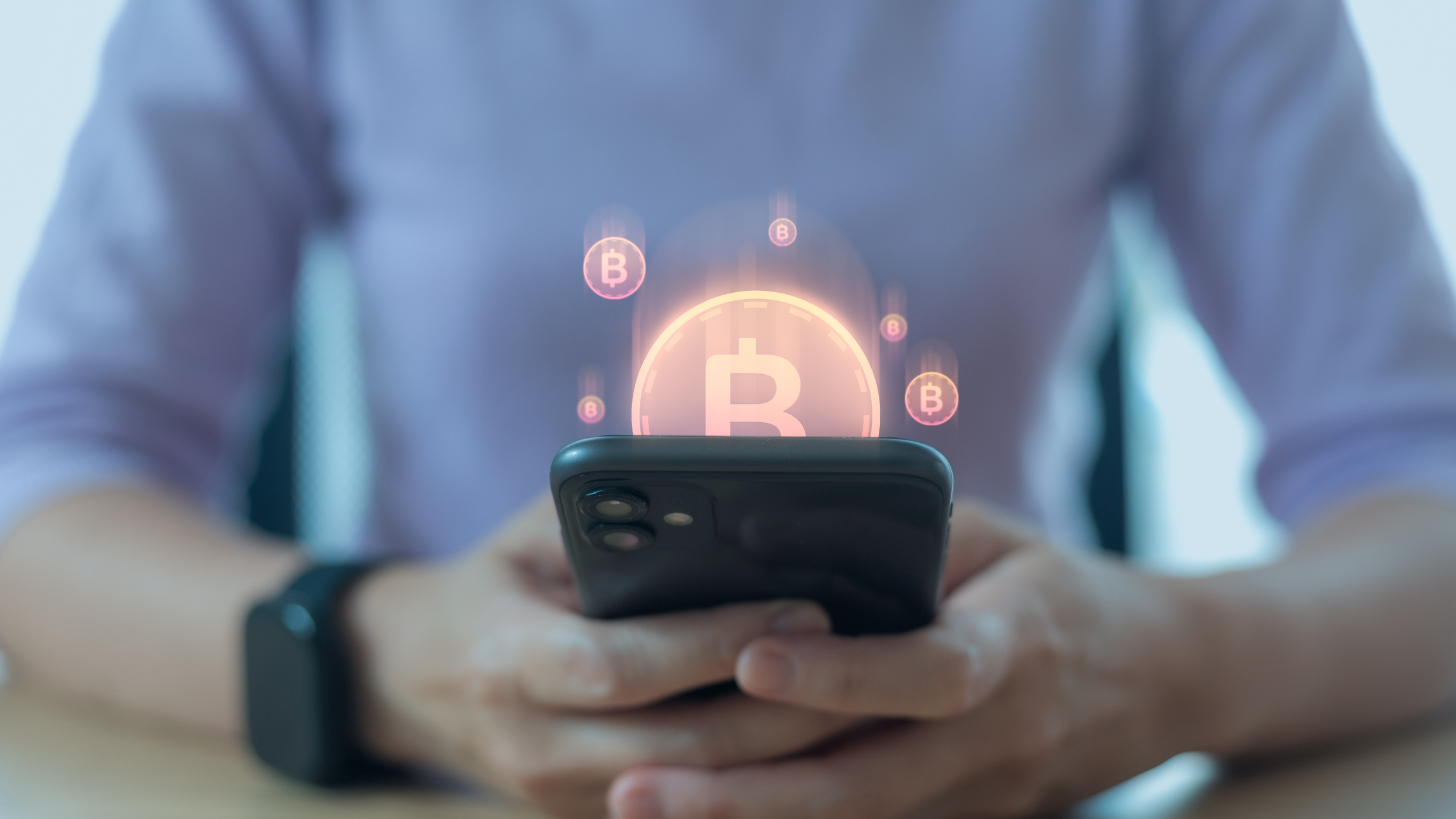 Hand holding smartphone with bitcoin hologram, concept of cryptocurrency and online investment
